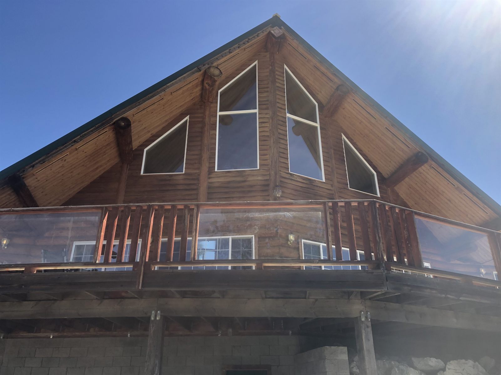Exterior of the log home showing the A-frame gable and tall windows.