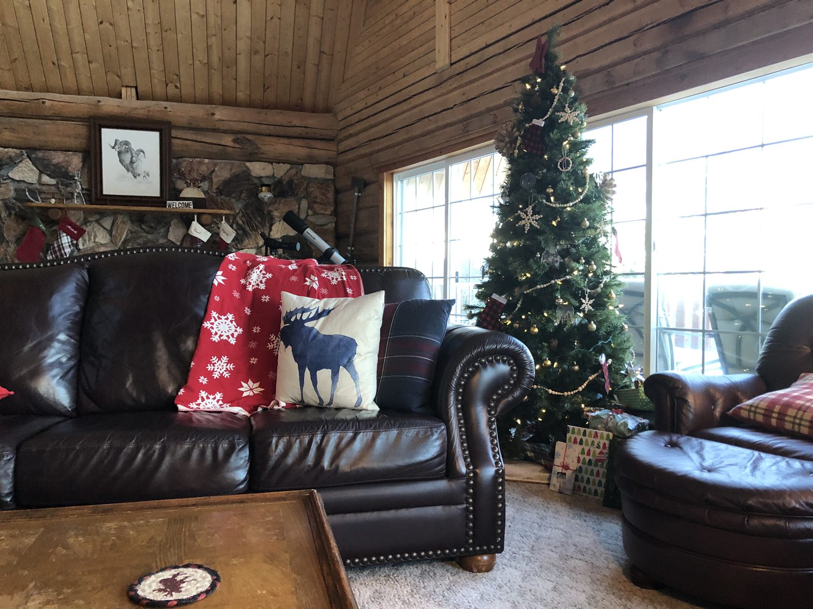 The great room interior with log walls, leather seating, and large windows.