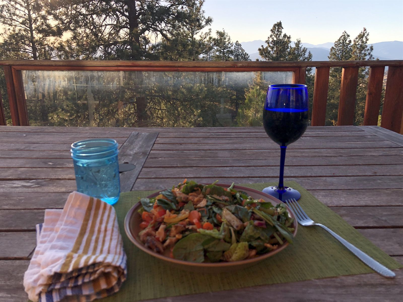 Dinner and wine set on the deck table at sunset, overlooking the valley.